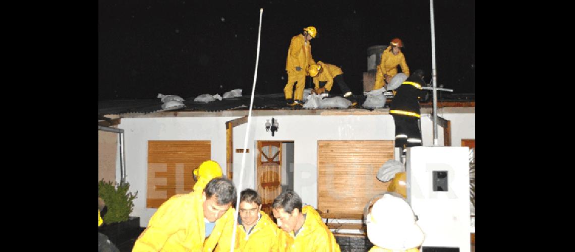 Momento que colocan bolsas de arena sobre las chapas en una viviendas mÃs afectadas en Los Robles 