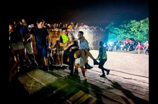 Unos hombres cargan a una mujer afectada tras un tiroteo registrado en un evento musical hoy en San Bernardino